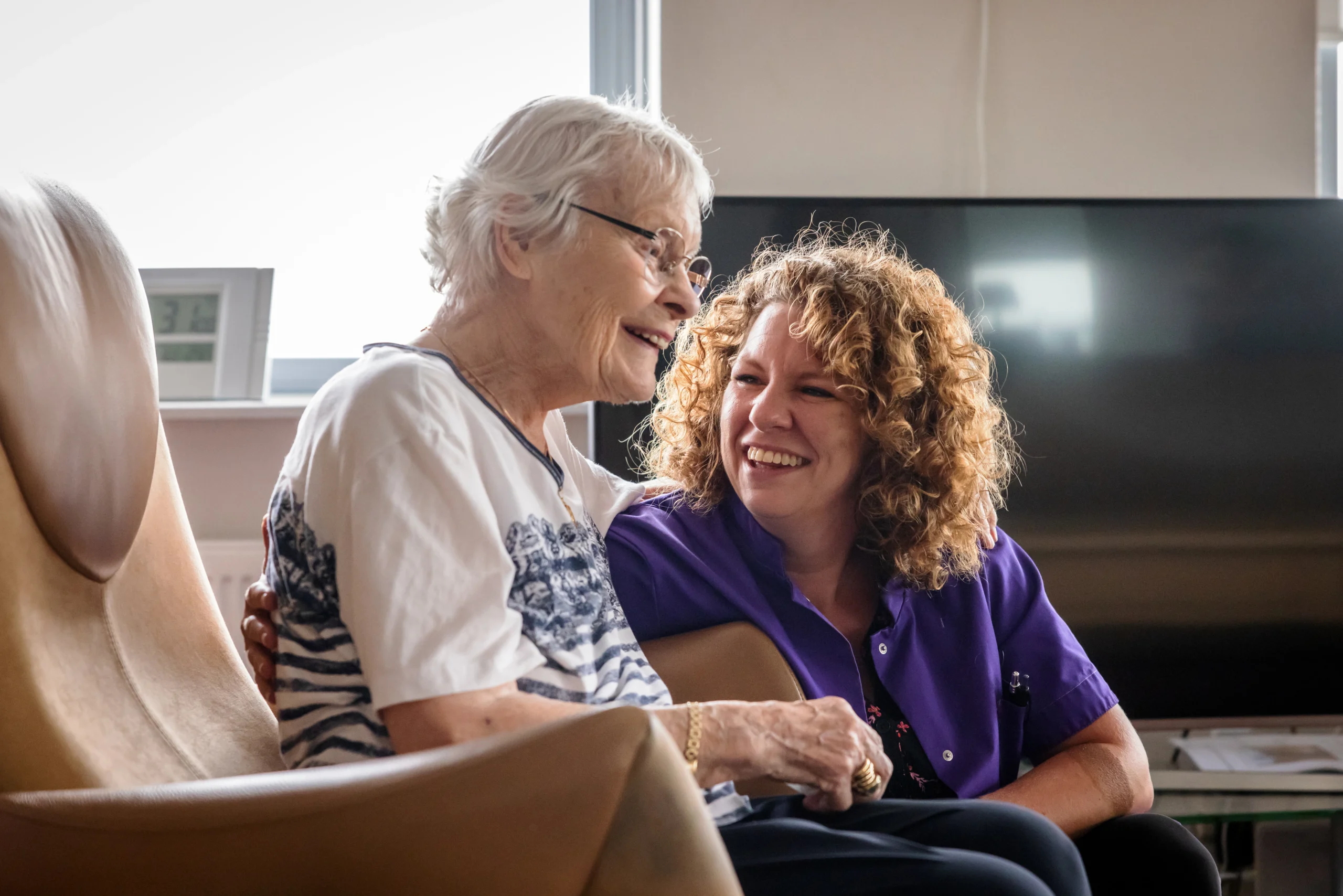 Zorgcollega van Topaz lacht naar een bewoner