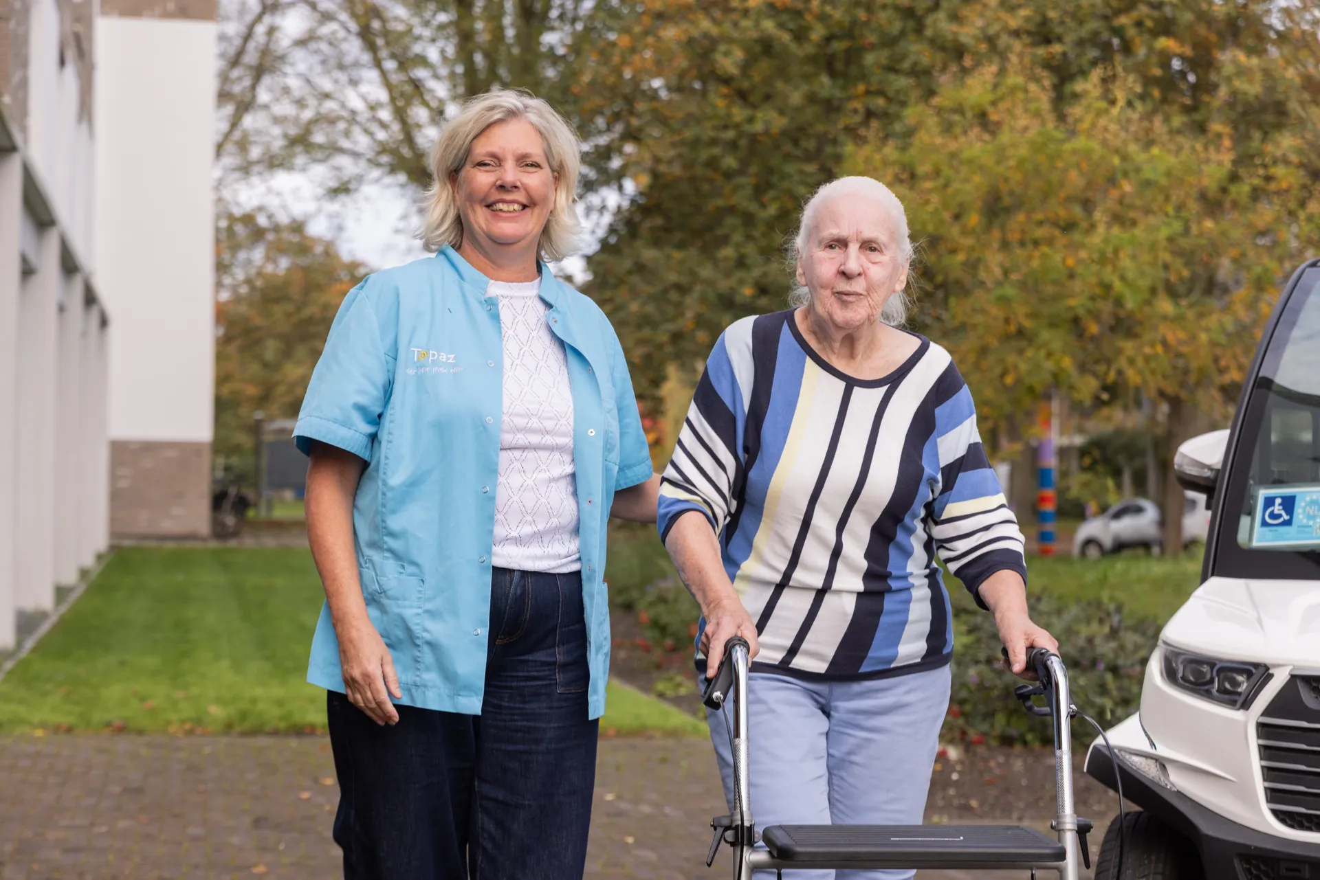 zorgmedewerker van topaz samen met bewoner aan het wandelen buiten