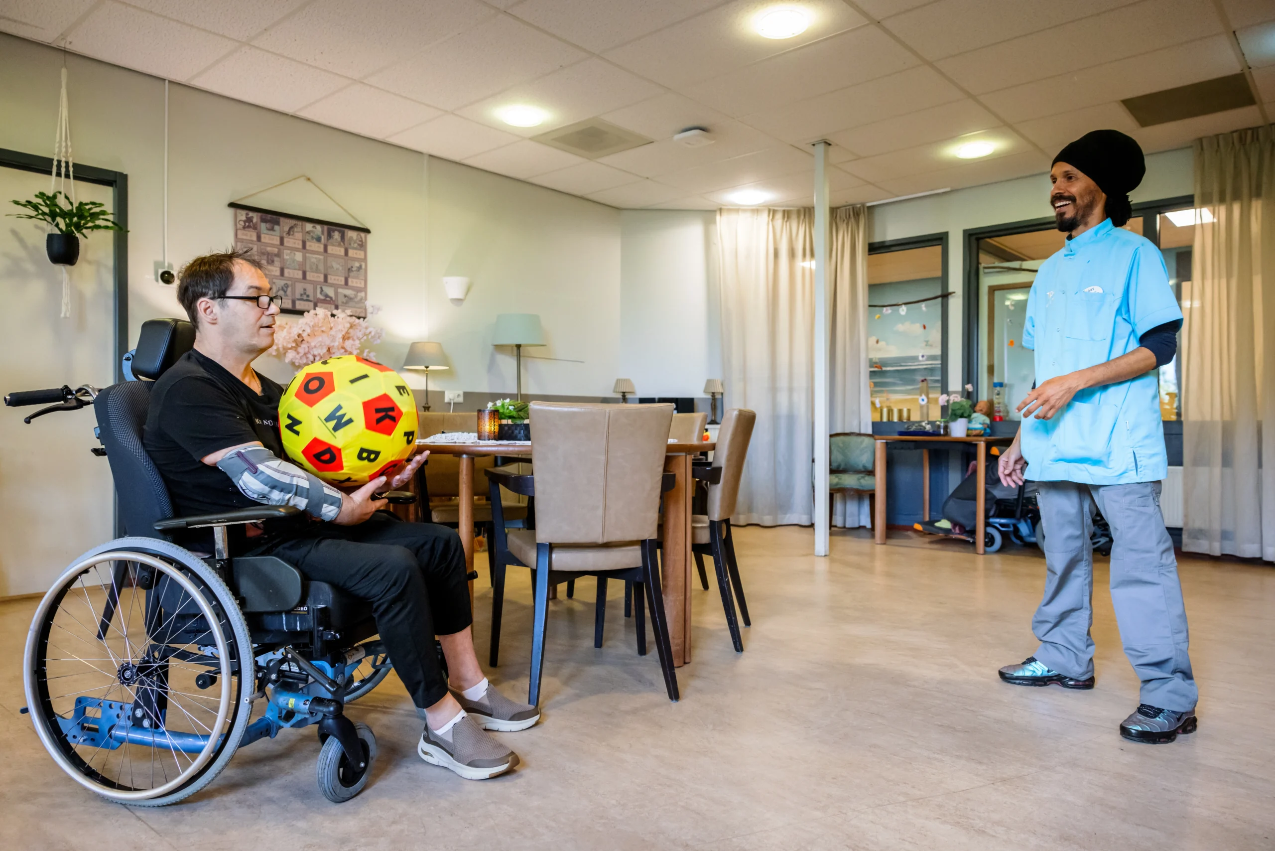 Zorgcollega van Topaz gooit een bal over met een bewoner