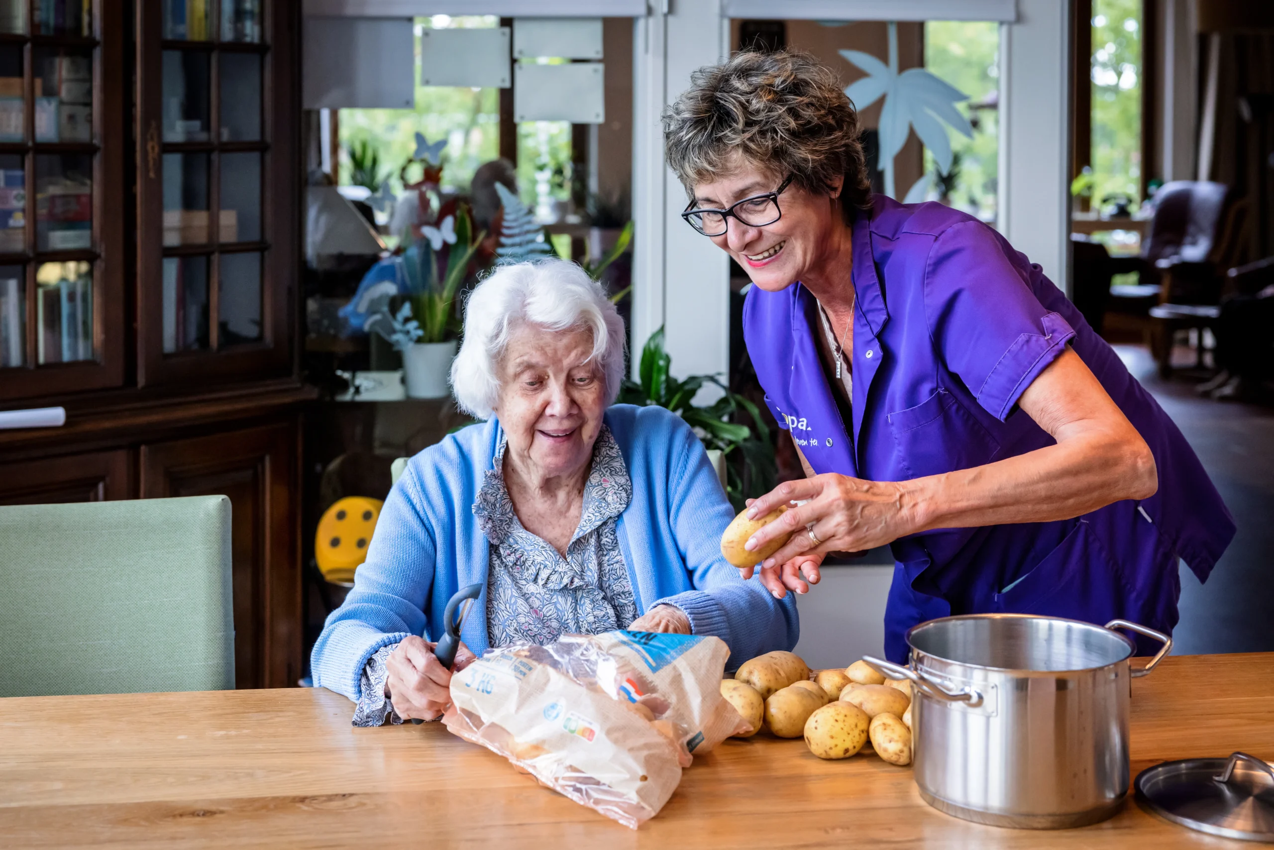 zorgcollega van topaz schilt samen met een bewoner de aardappels