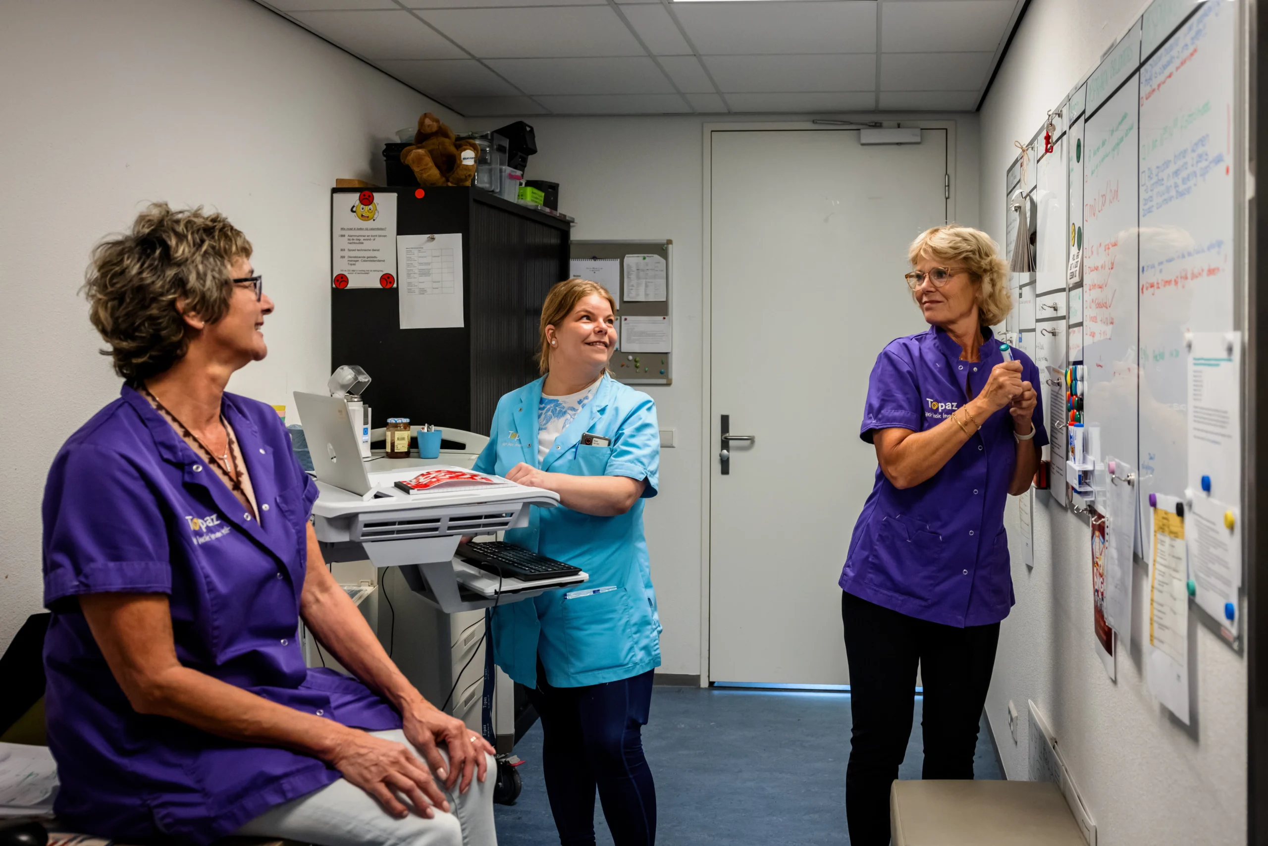 drie zorgmedewerkers in overleg met elkaar 