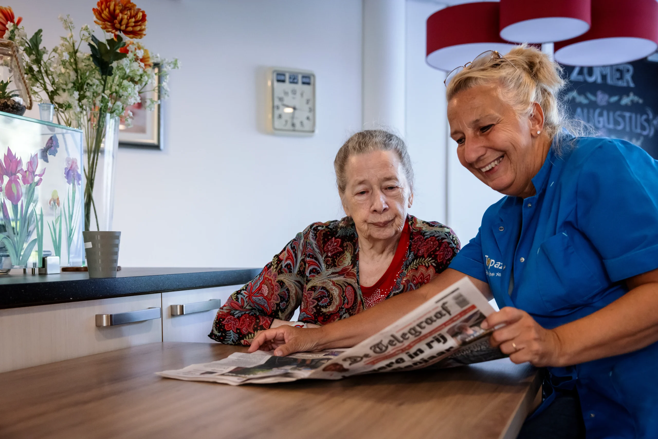 zorgcollega van topaz leest de krant met een bewoner